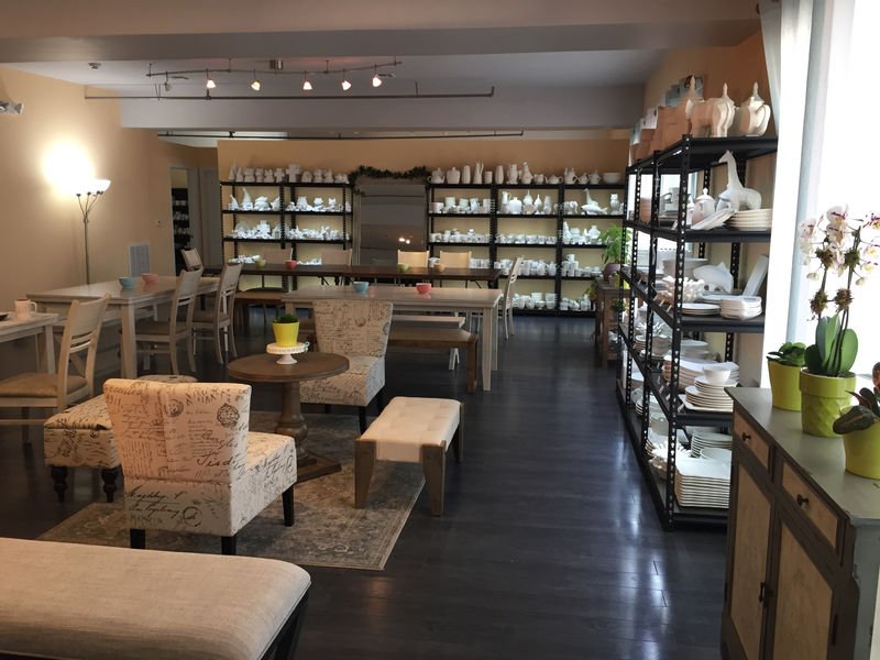 Tables and shelves of ceramic pieces inside Painting Pottery Cafe.