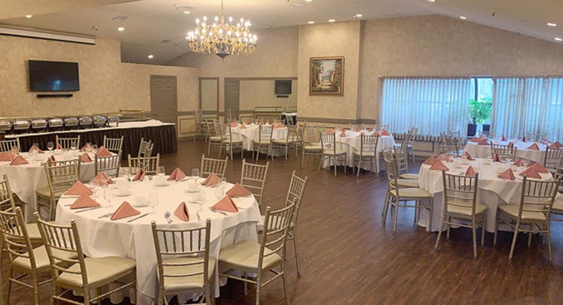 Round tables with white tablecloths and pink napkins in Biagio’s Banquet Room.